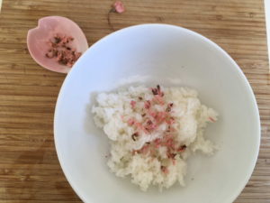 Gehackte Kirschblüten auf den gekochten und noch heißen Reis streuen